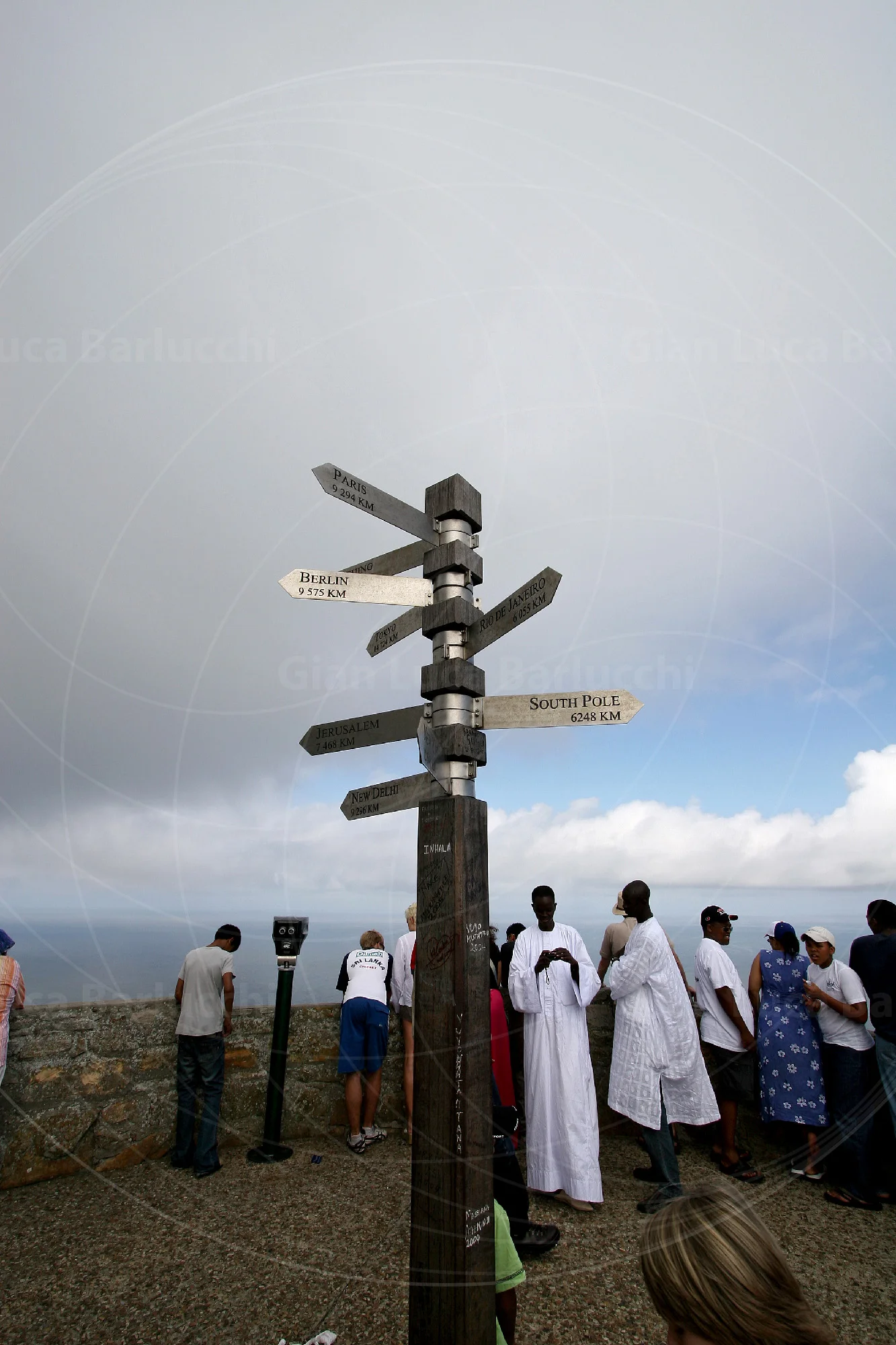 Wooden signpost on a hilltop with a group of people in the background