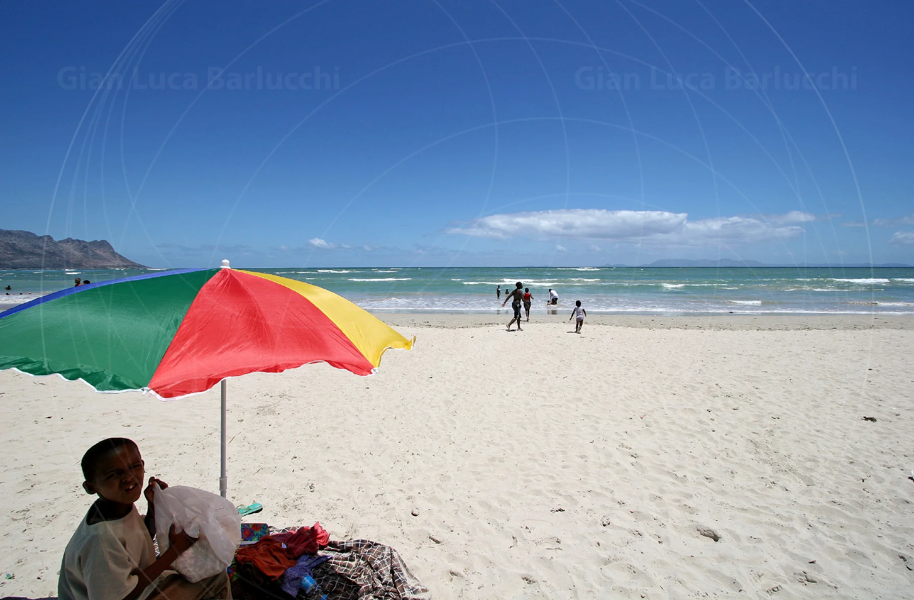 Colourful beach umbrella beside the sea and pale sand at Gordon's Bay