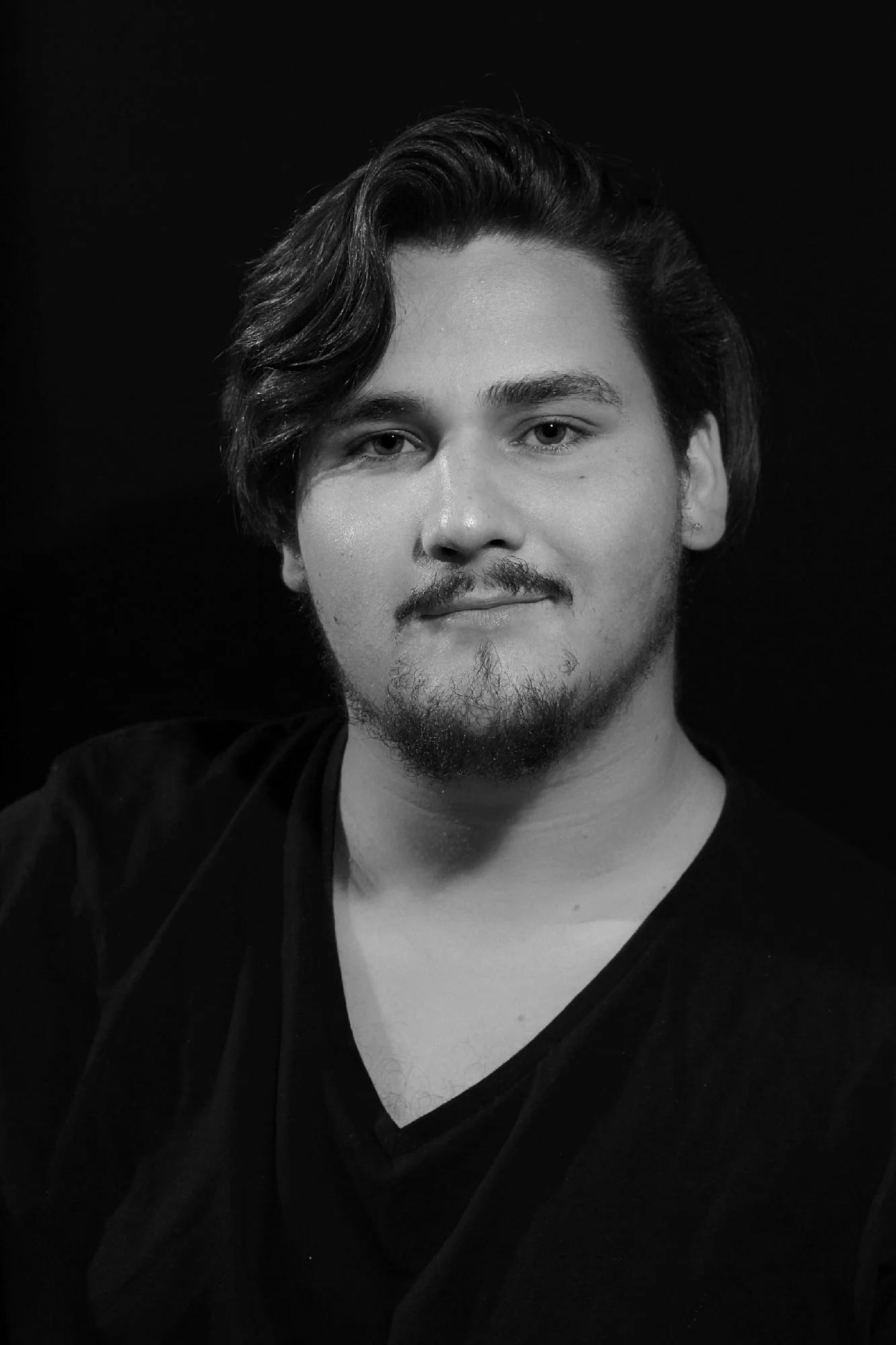Black-and-white portrait of a young man in a dark V-neck shirt