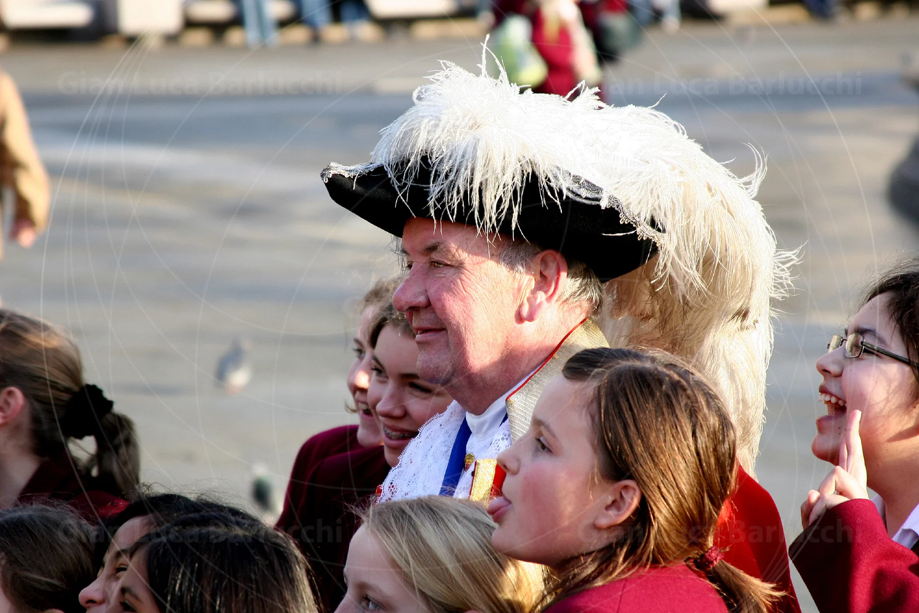 Man in a feathered historical hat surrounded by a crowd