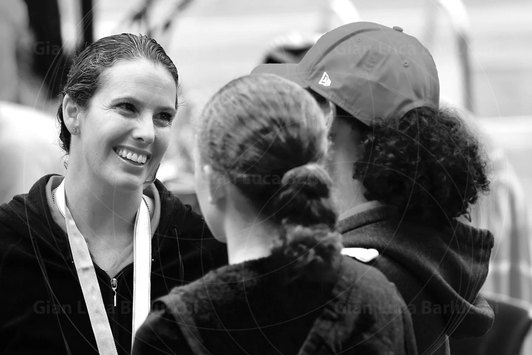 Black-and-white photograph of a smiling woman speaking with two people