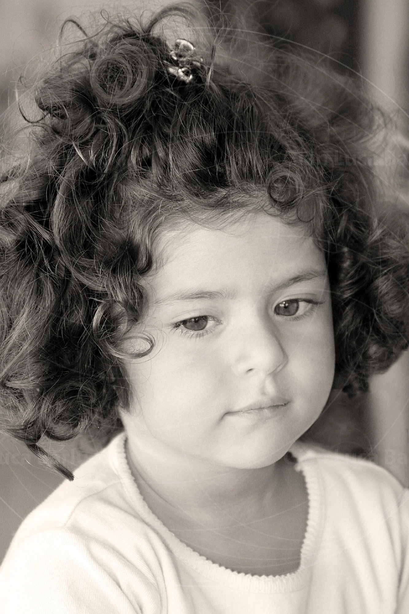 Black-and-white portrait of a young child with curly hair tied up