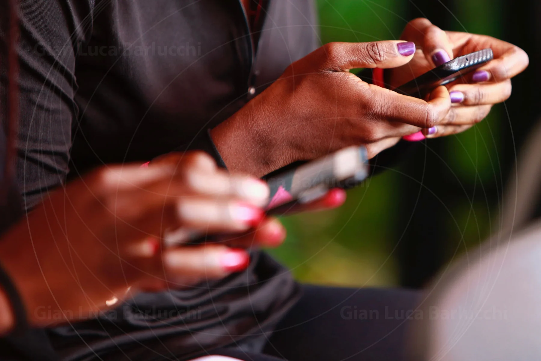 Hands holding mobile phones in warm sunlight
