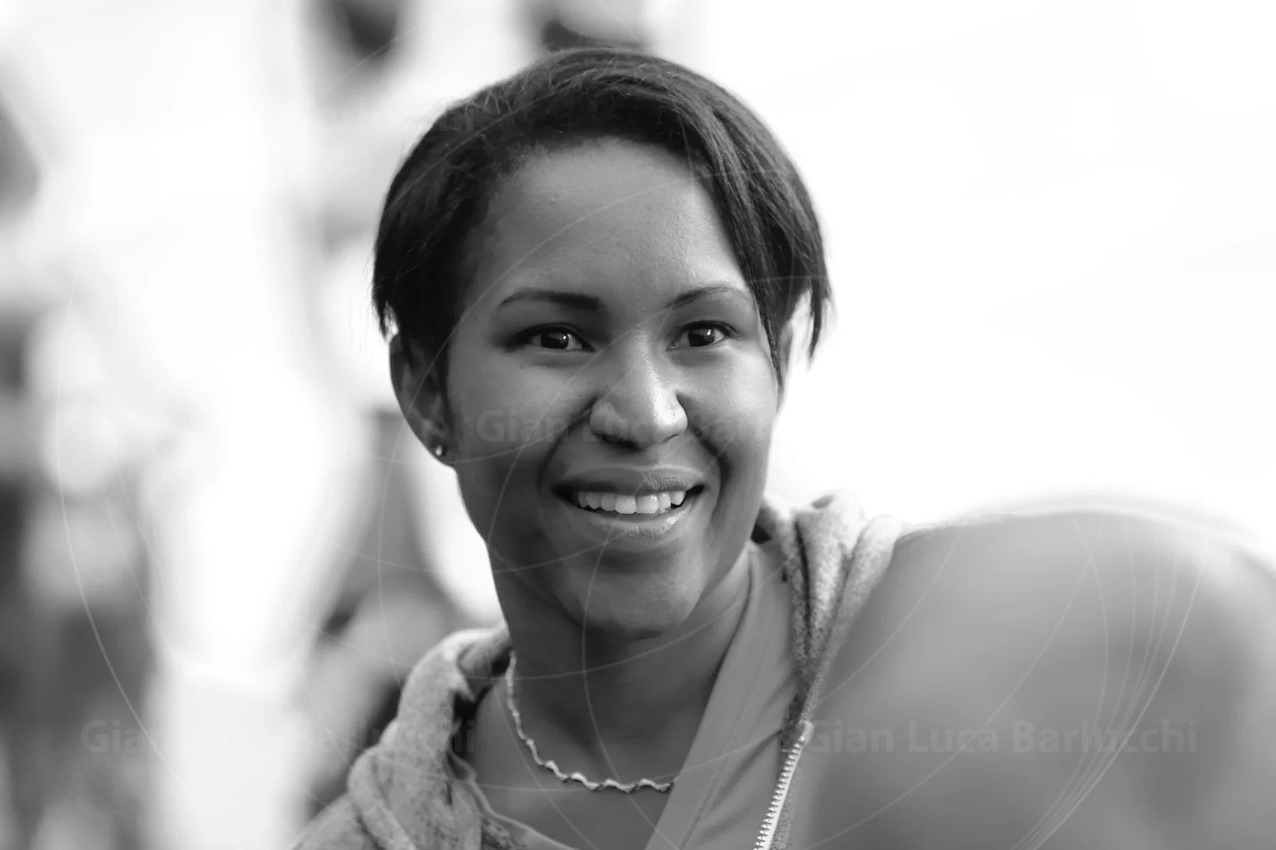 Black-and-white portrait of a smiling woman wearing a necklace