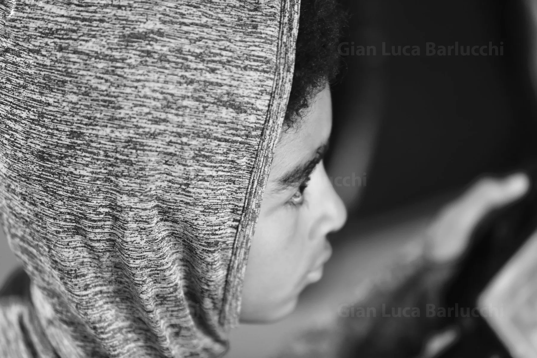 Black-and-white profile of a child with a hood pulled over their head