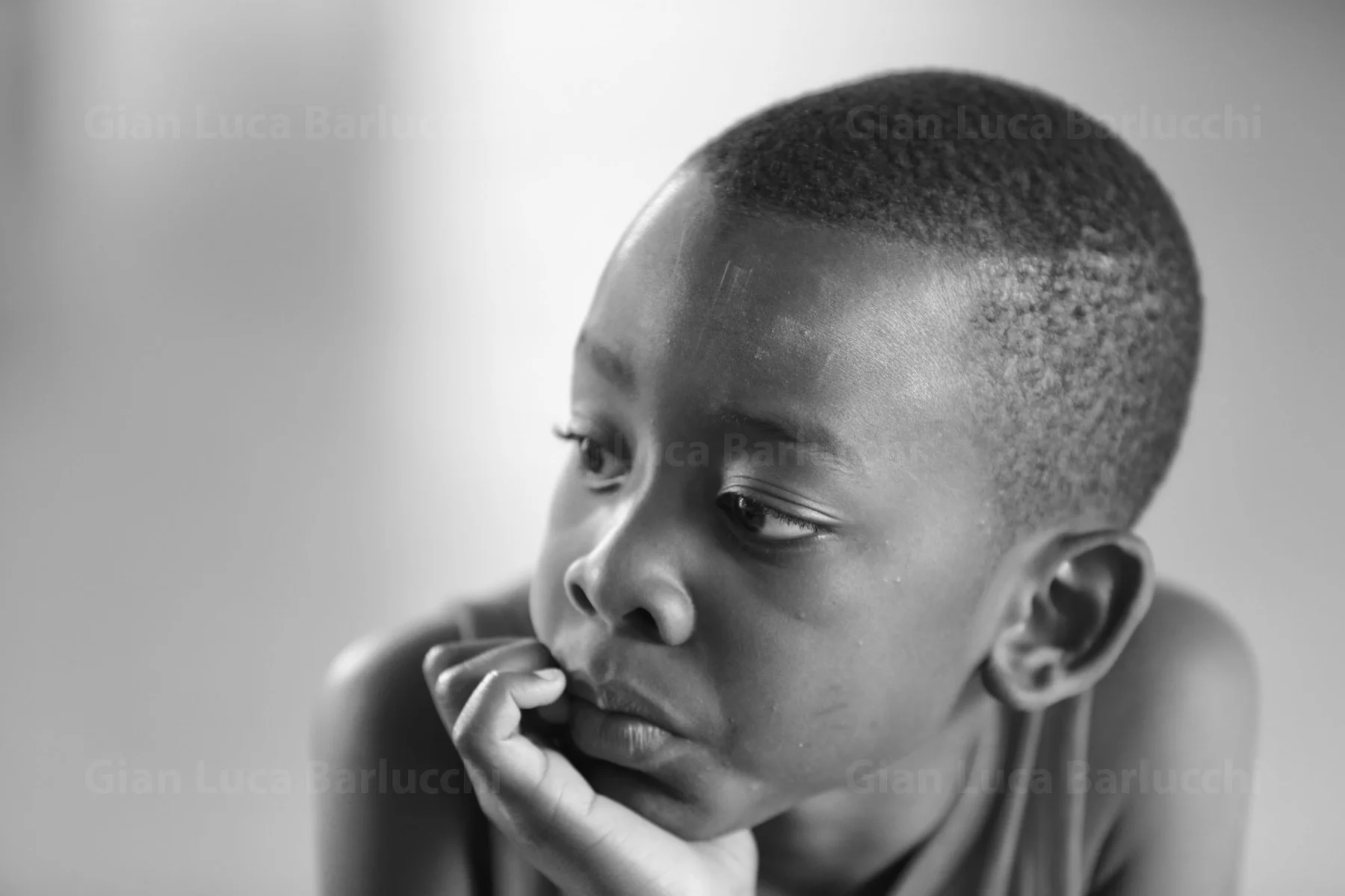 Black-and-white portrait of a child resting their chin on one hand