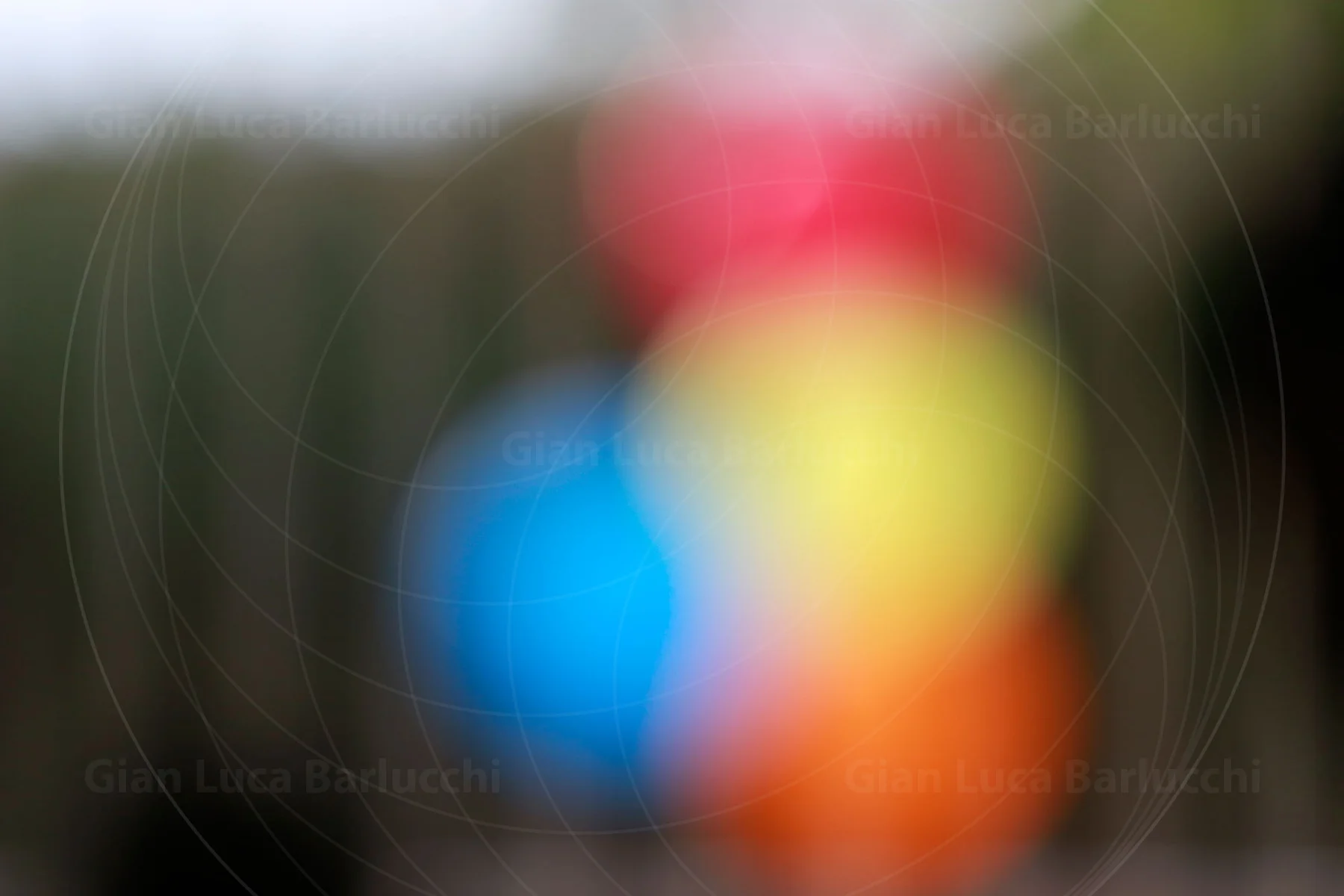 Softly blurred red, yellow and blue objects against a green background