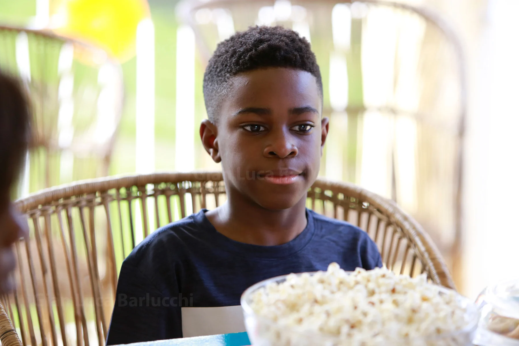 Young person seated behind a bowl of popcorn