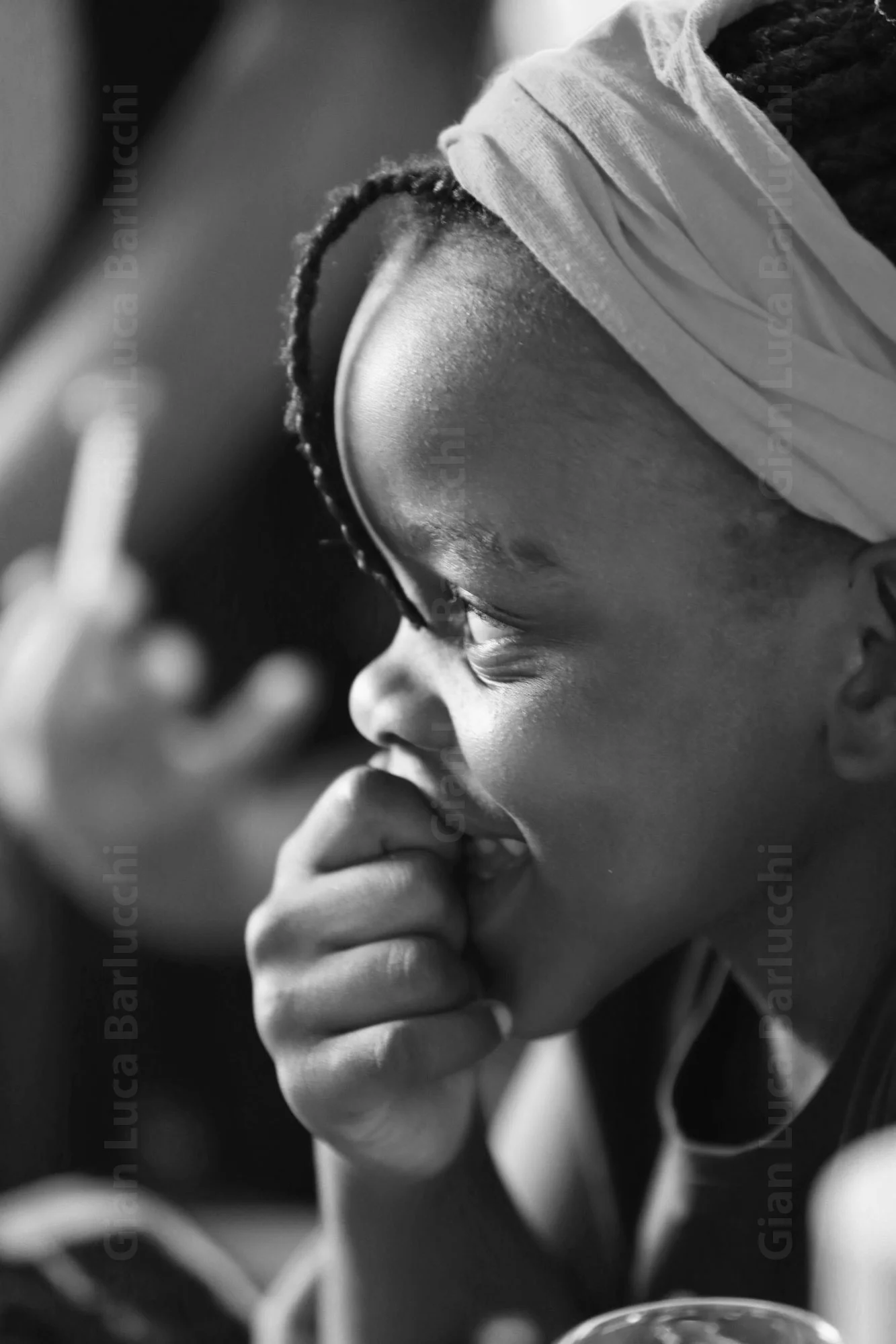 Black-and-white profile of a child in a headband with a hand near their mouth
