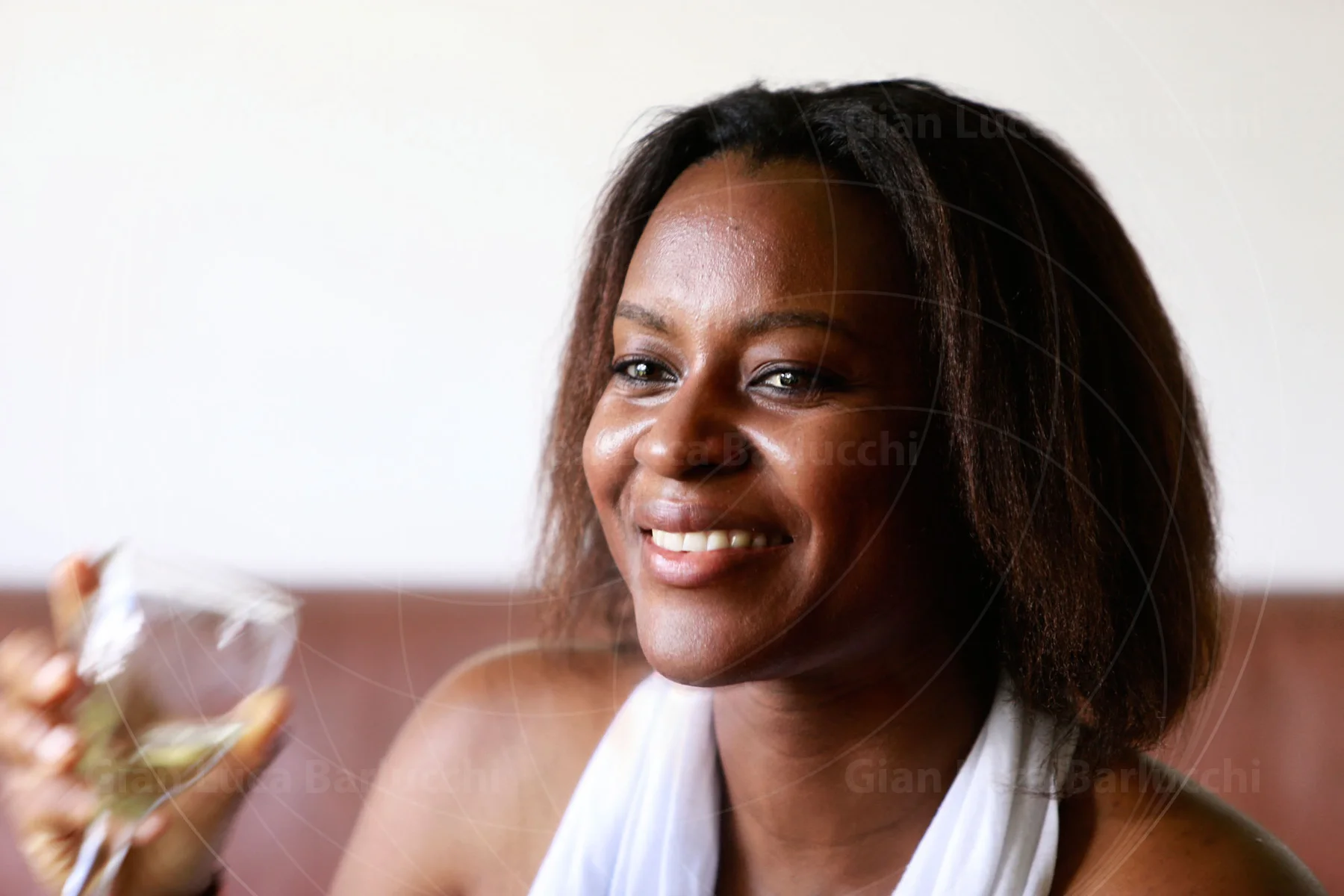 Smiling woman seated indoors holding a glass