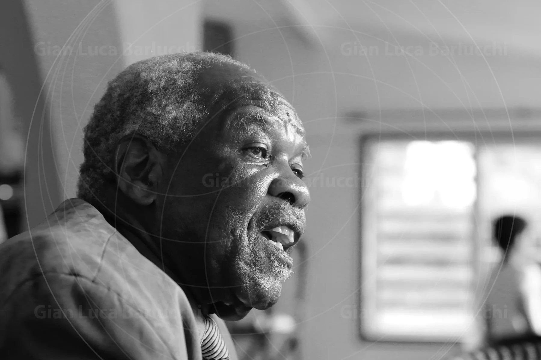 Black-and-white portrait of an older man with his mouth open mid-expression