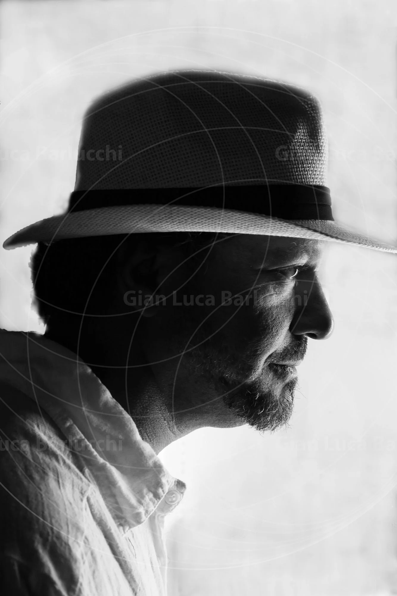 Black-and-white profile of a man wearing a dark hat