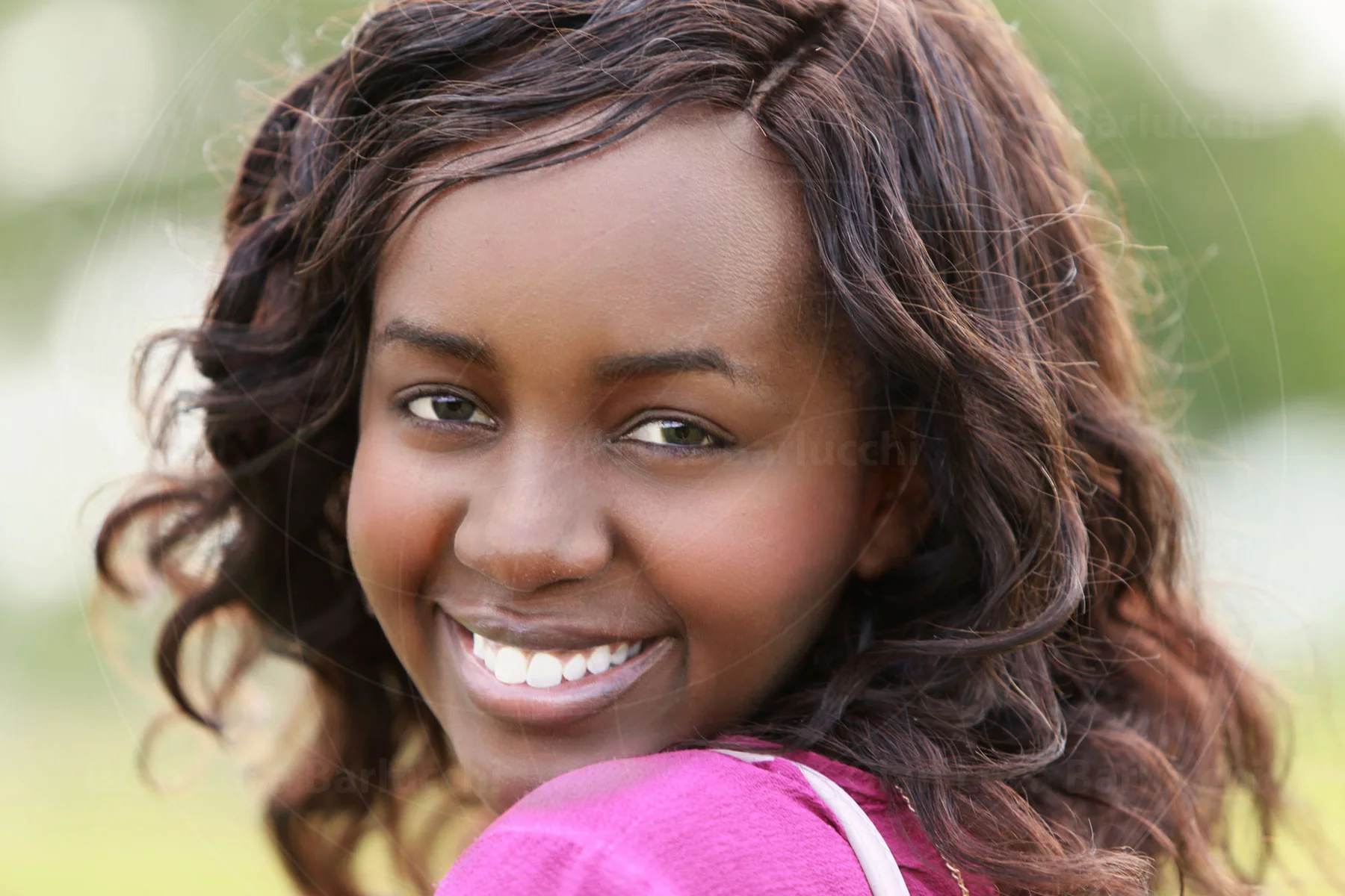Smiling woman in a pink top looking back over her shoulder