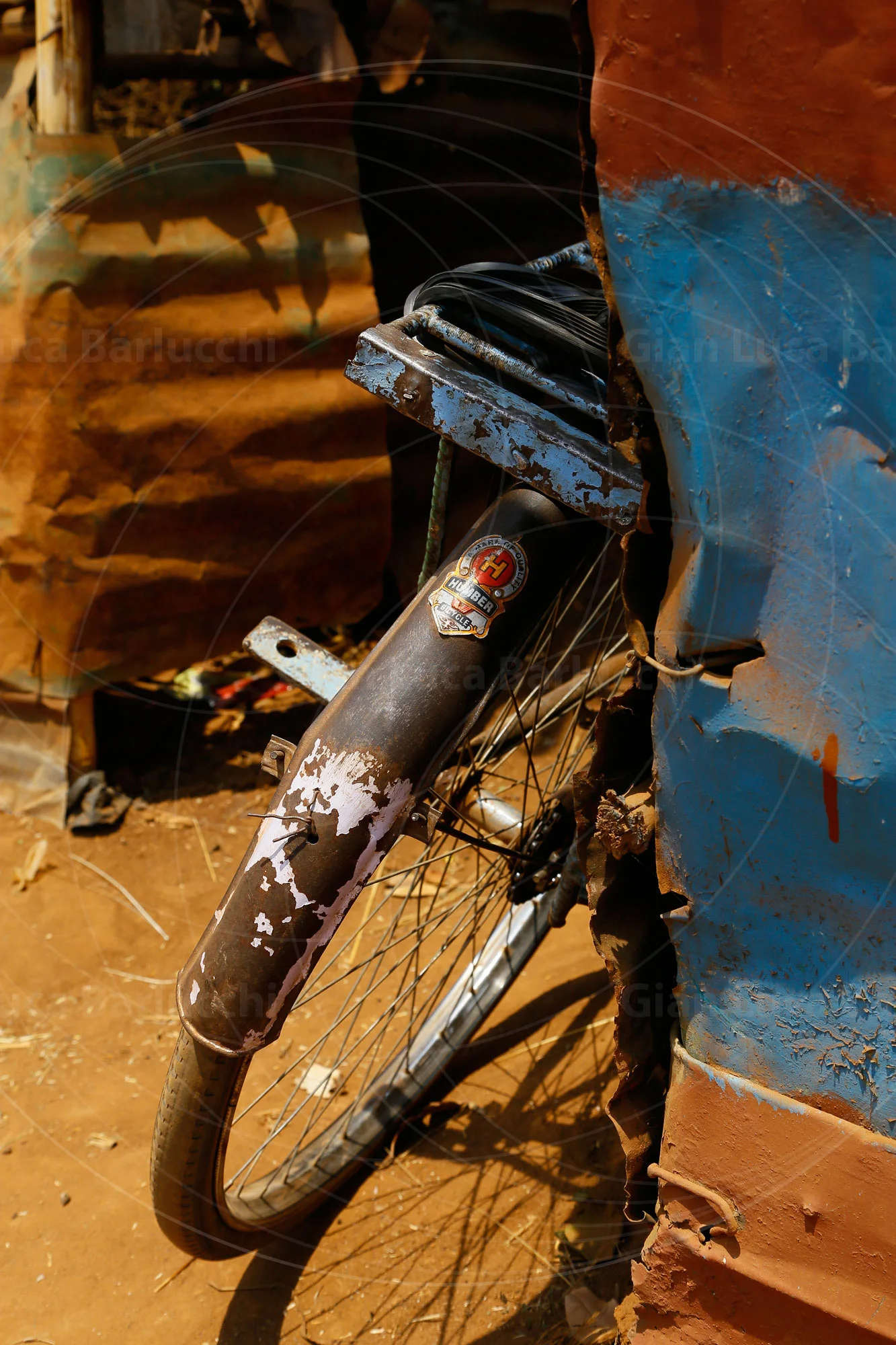 Bicycle wheel leaning beside a weathered blue metal panel