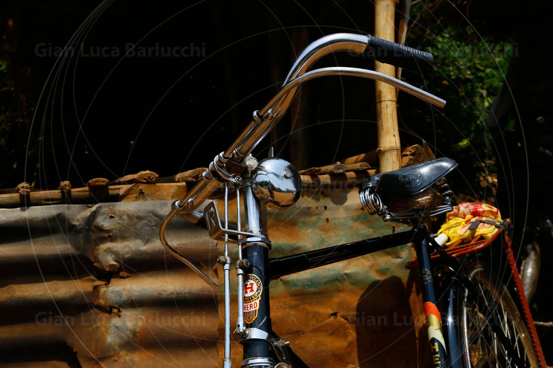Bicycle handlebars and saddles beside a corrugated metal fence
