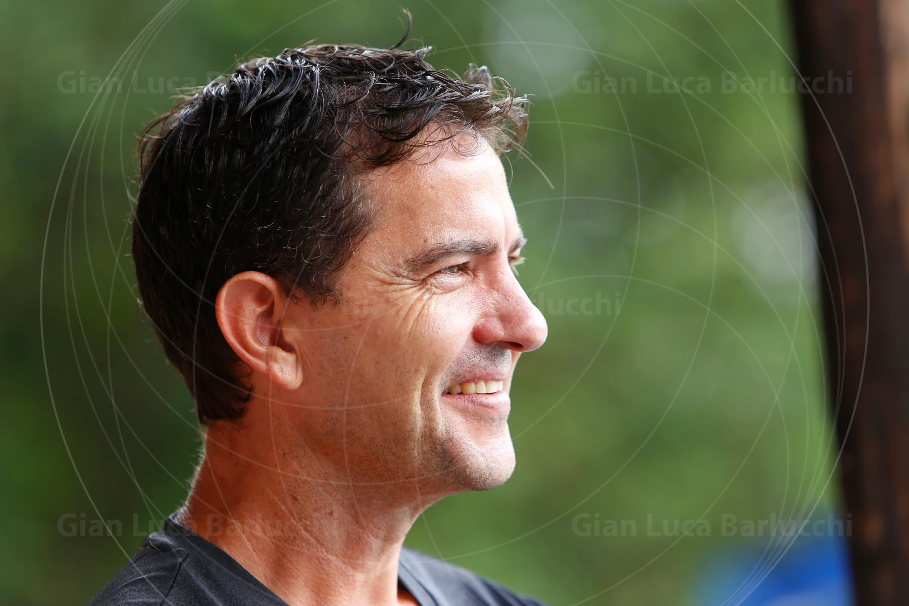 Smiling man in profile against a green background