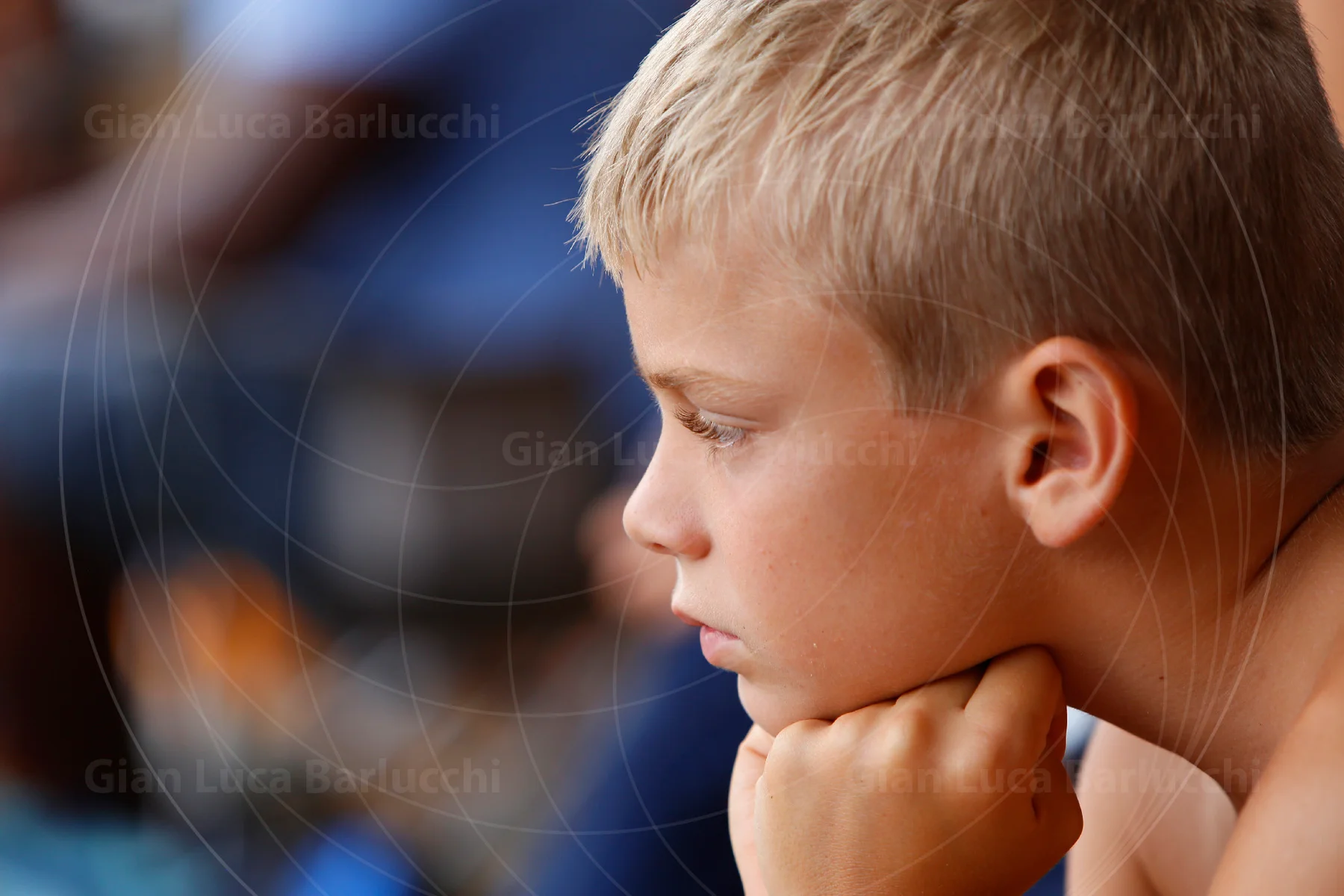 Blond child resting their chin on their hands and looking to the side