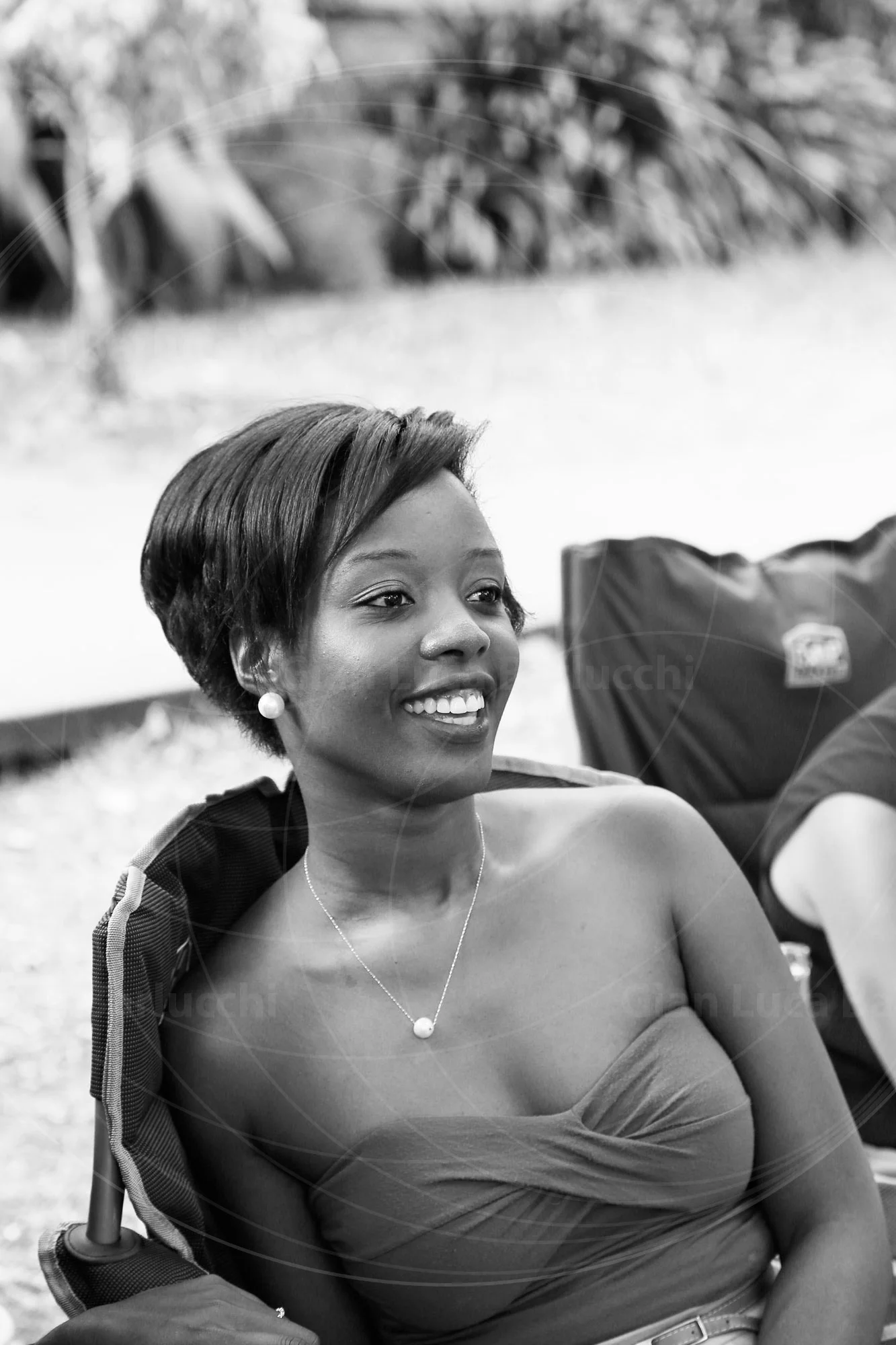 Black-and-white photograph of a smiling woman seated outdoors