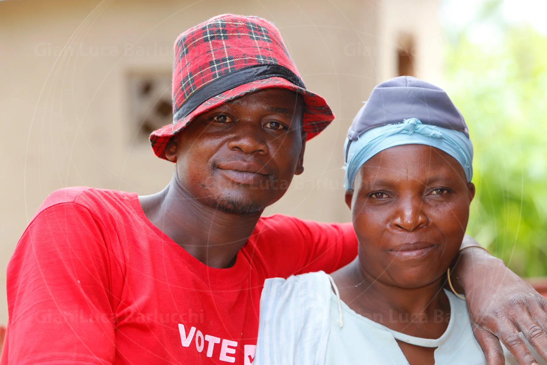 Two people in colourful hats standing with an arm around one another