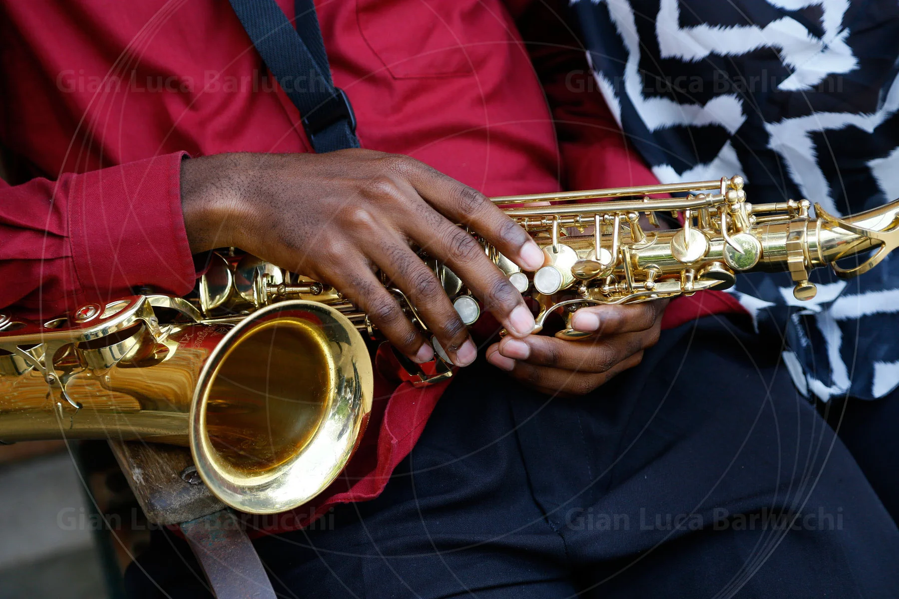 Hands resting on a golden saxophone across a musician's lap