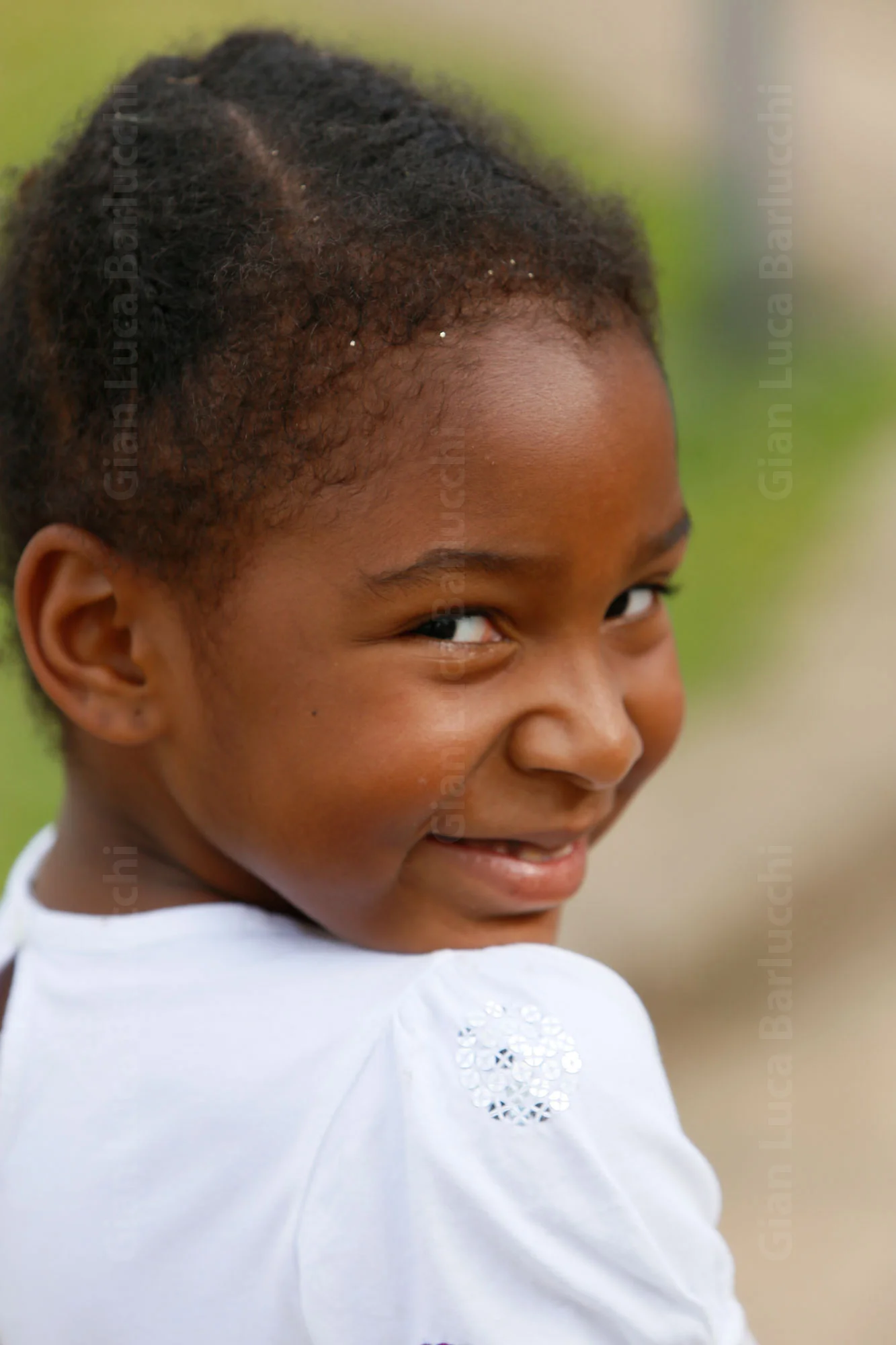 Child in a white top smiling back over their shoulder