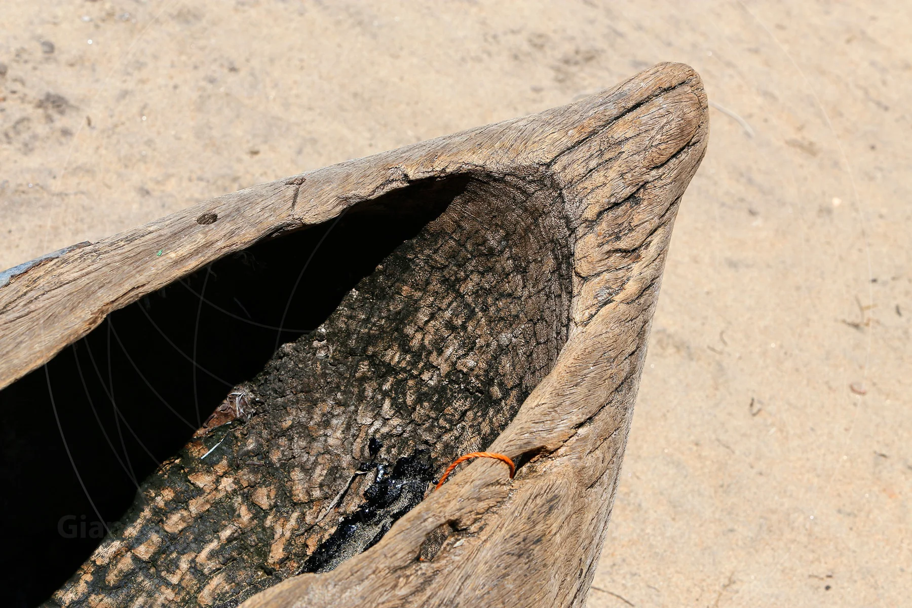 Worn wooden canoe with fishing net tucked inside its bow